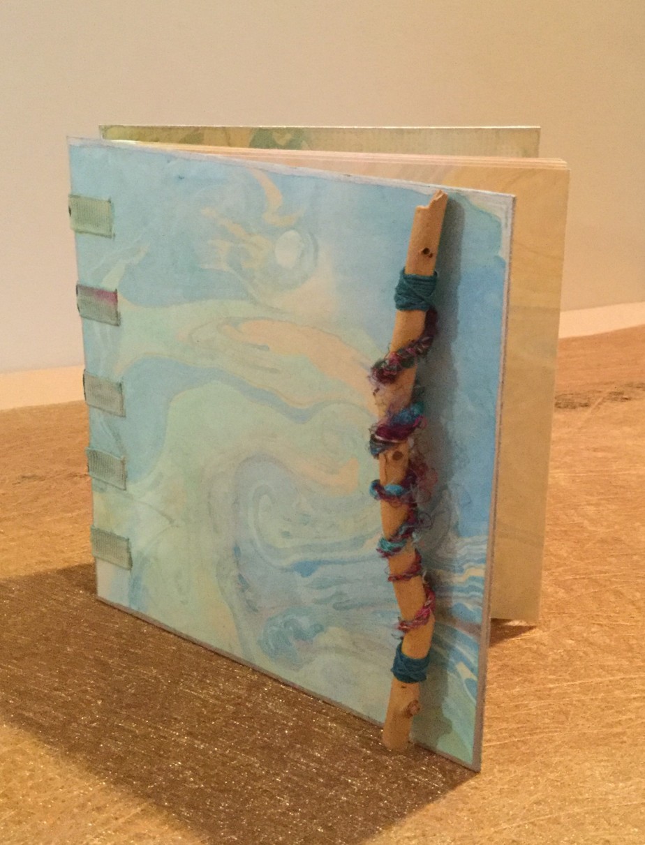 I finally got around to finishing the last detail on the marbled book. A twig and some silk yarn are all it needed.